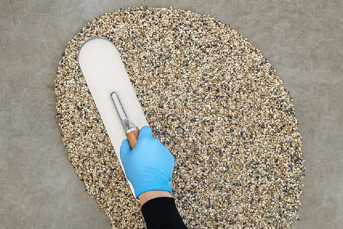 Eine Person verlegt einen Steinteppich mit Epoxidharz